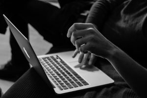 Black and white close-up of hands on the keyboard of a laptop computer